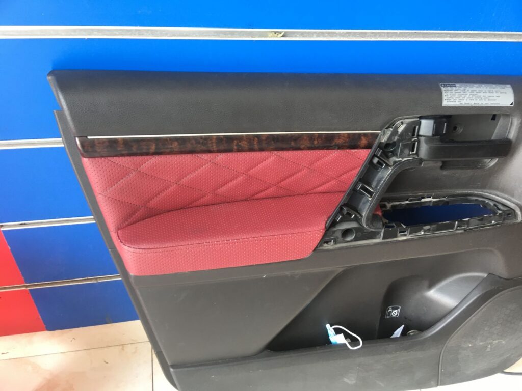 The interior of a car featuring a red leather seat and detailed car upholstery, with a glimpse of the car door visible.