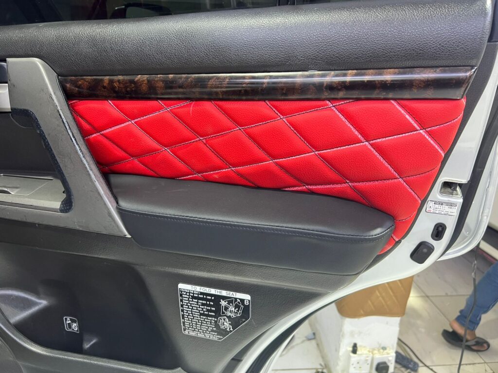 A close-up of a car door featuring luxurious red and black quilted leather upholstery, showcasing elegant craftsmanship.