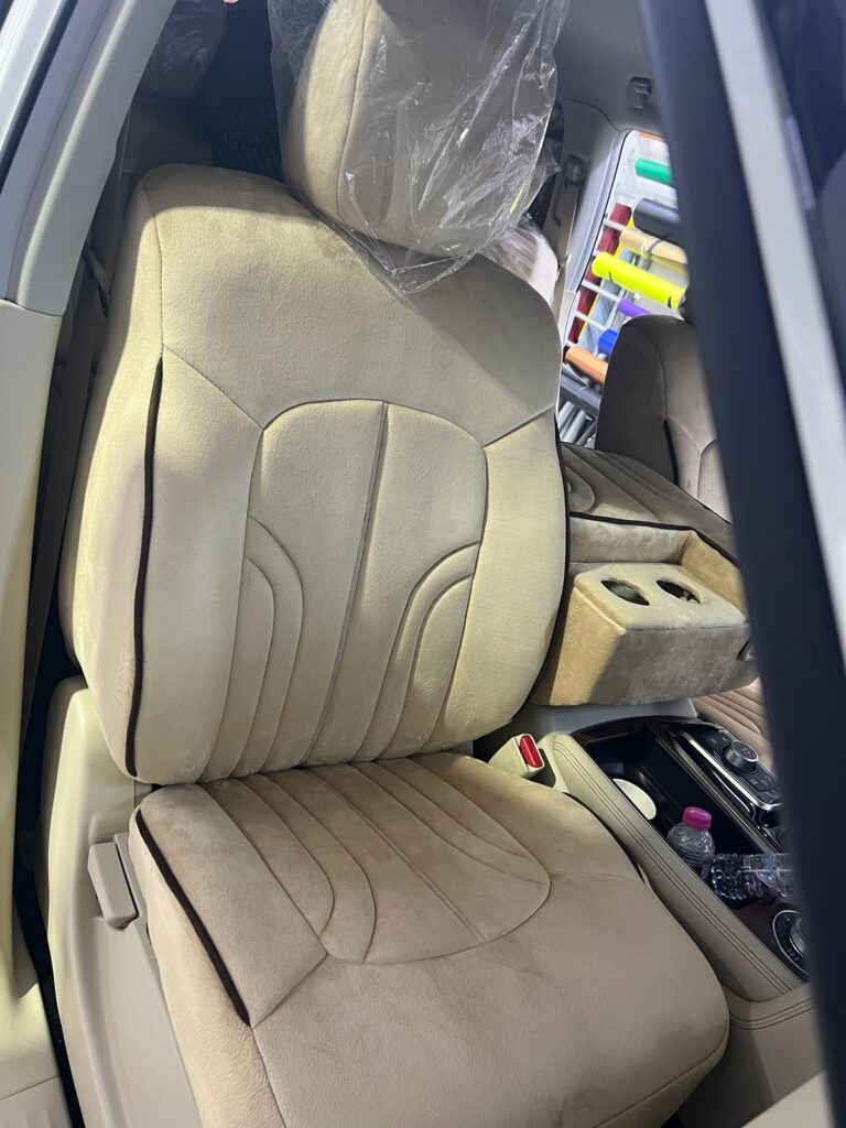 The front seat of a brand-new car is covered in clear plastic, preserving the pristine upholstery underneath.