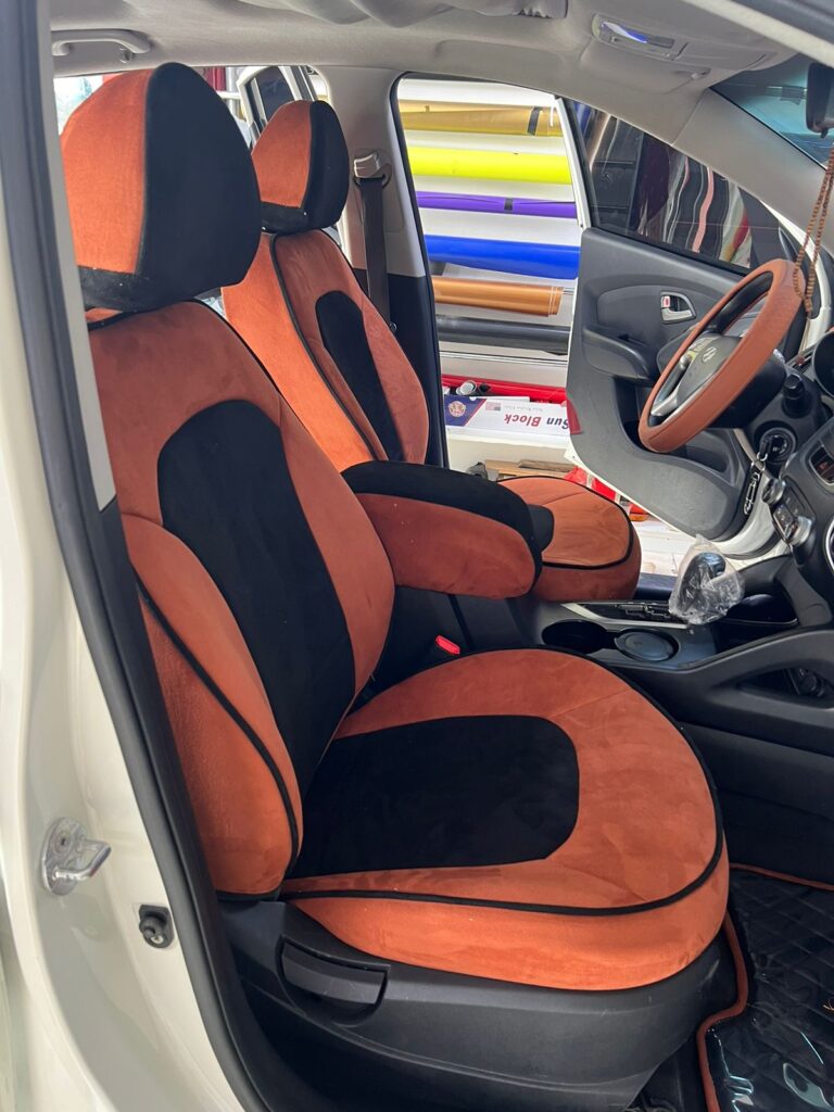 A car interior featuring distinctive orange and black upholstery on the seats, showcasing a modern design aesthetic.