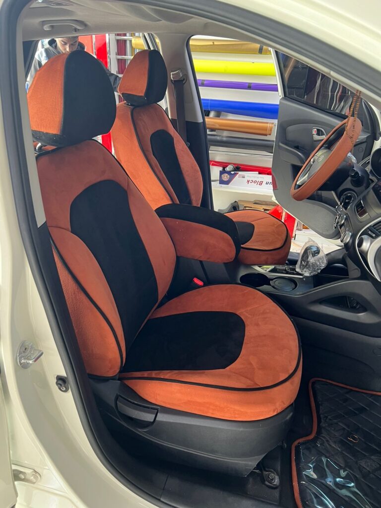 A four-seater car featuring a stylish black and brown seat cover, showcasing elegant car upholstery design.