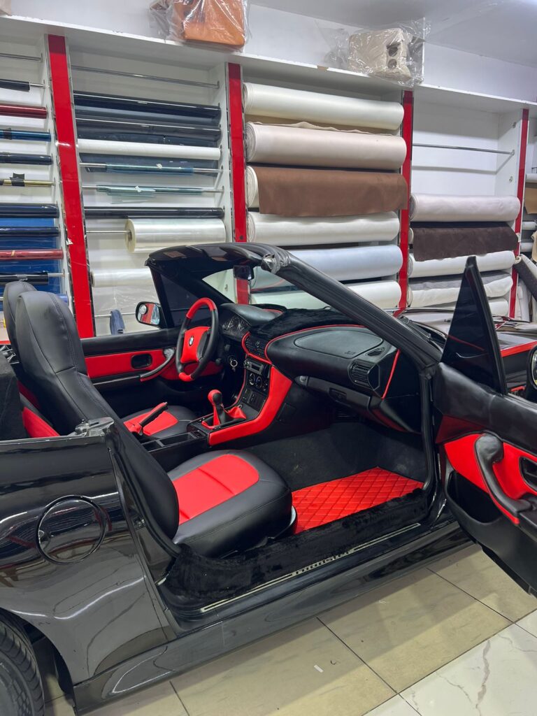 A black and red sports car with open doors, showcasing premium upholstery inside Al Badiya shop.