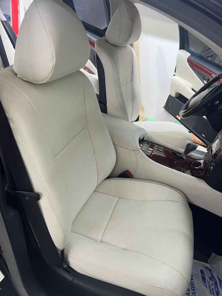 A close-up view of a car interior showcasing white leather seats with elegant black trim, highlighting the upholstery design.