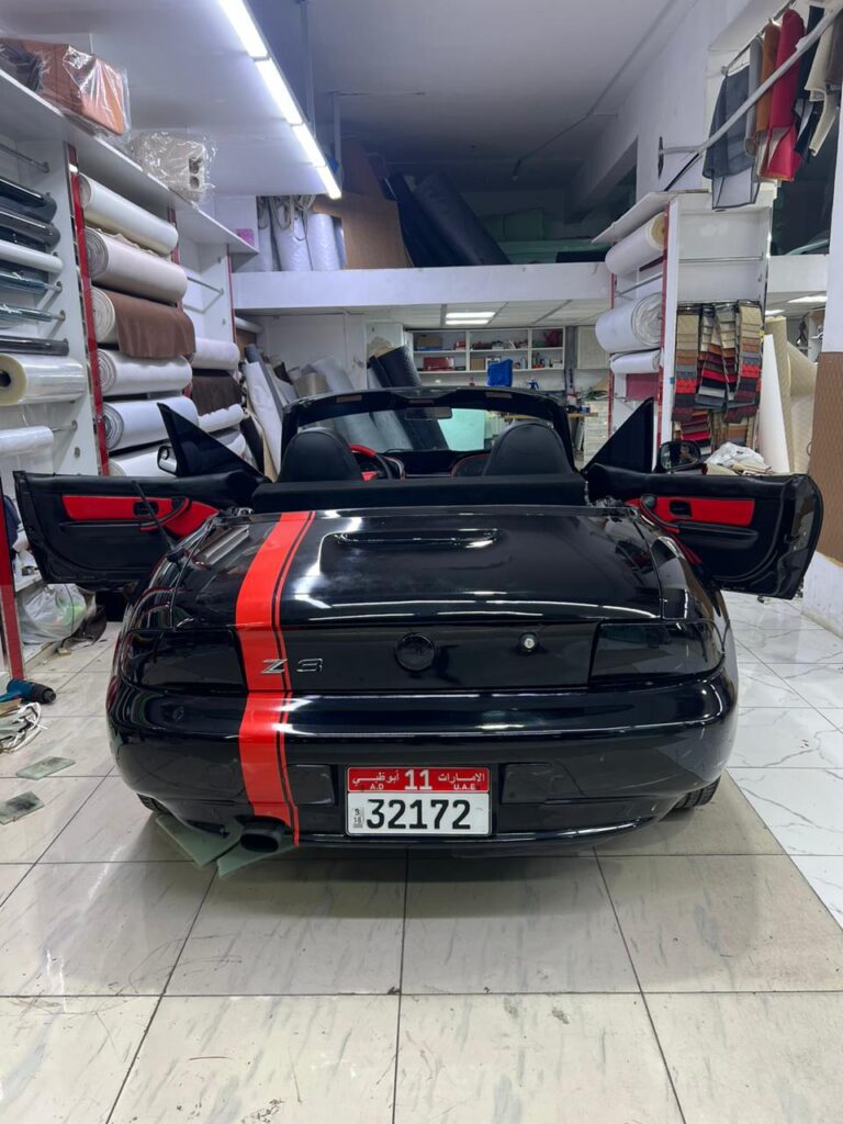 A sleek black sports car featuring striking red stripes on the hood, showcased at AlBadiya shop in Abu Dhabi.