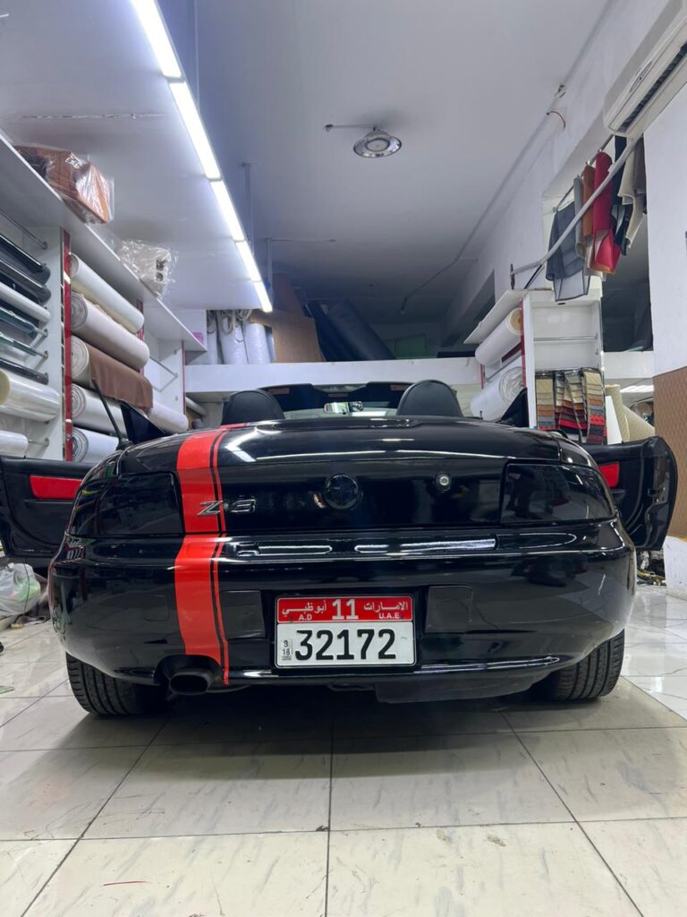 A sleek black sports car featuring striking red stripes on the rear, showcasing a stylish car wrap design.