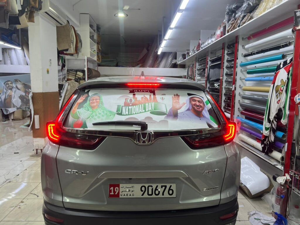 A car displaying a large banner on its back, celebrating the National Day of the UAE.