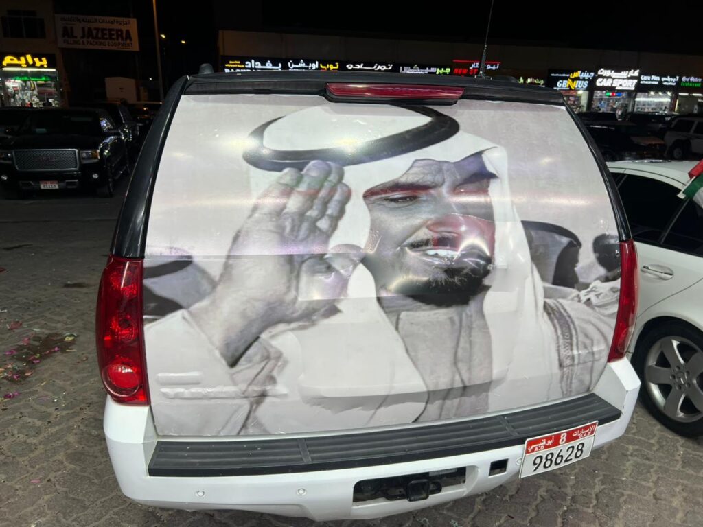 A car featuring a vibrant wrap displaying an image of the king on its rear side, showcasing royal imagery.