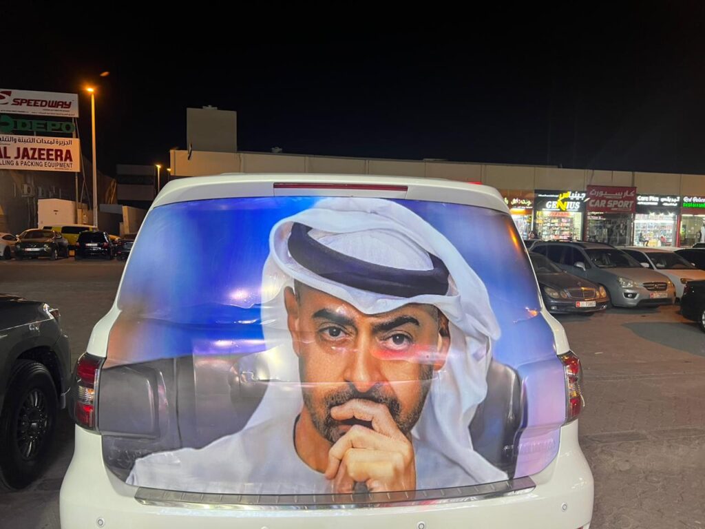 A car featuring a vibrant wrap displaying a painted portrait of a man on its rear side.