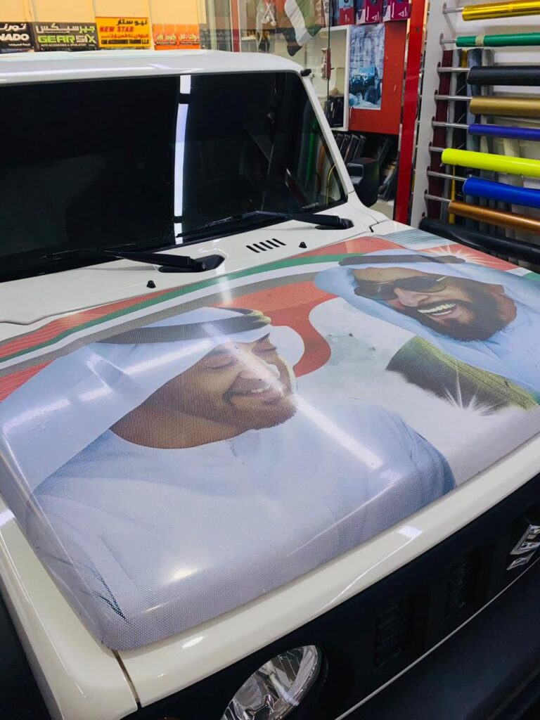 A car featuring a vibrant wrap displaying a large image of two men prominently on the hood.