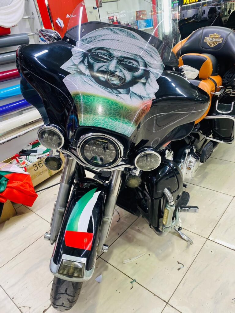 A motorcycle adorned with a face design and wrapped in the UAE flag is displayed inside a shop.