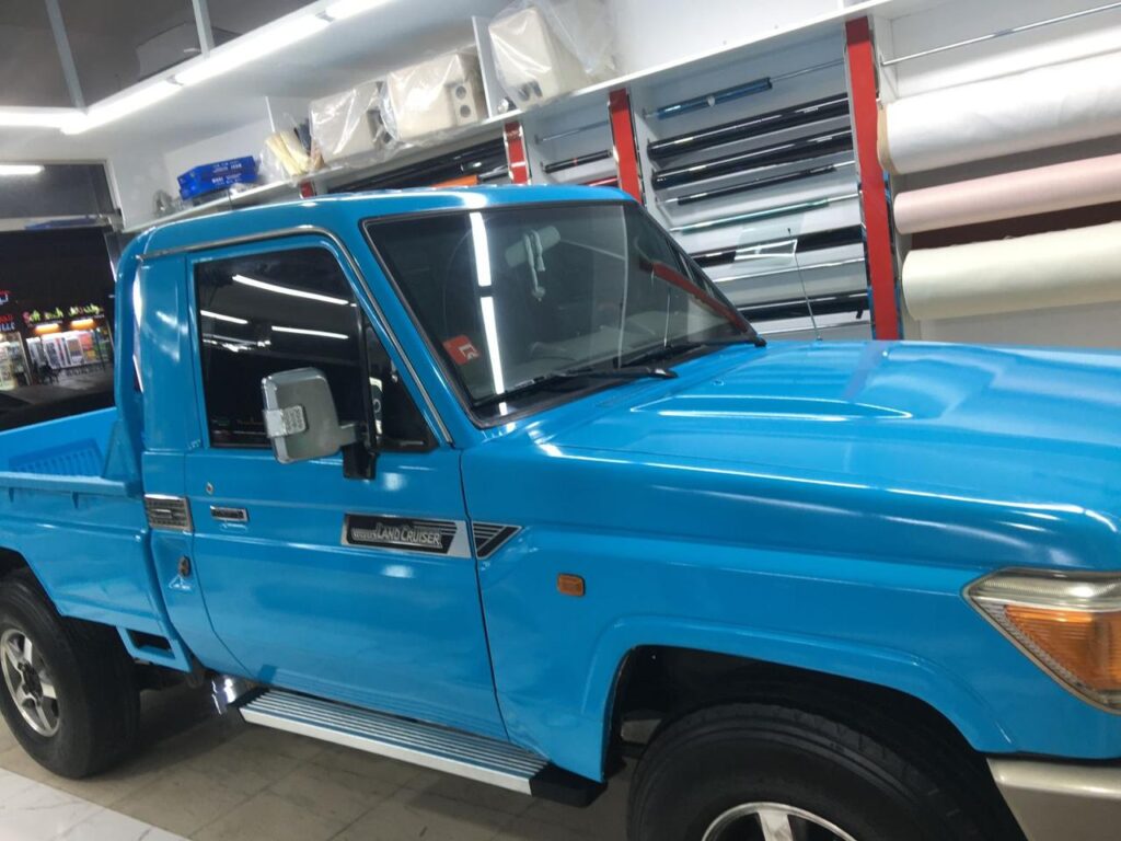 A blue Toyota pickup truck with a sleek car wrap parked elegantly in a modern showroom, showcasing its stunning design