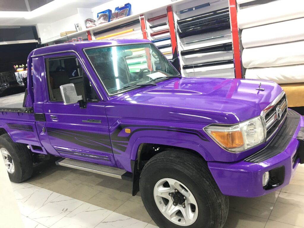 A vibrant purple Toyota truck showcased in a showroom, highlighting its stunning car wrap and eye-catching design.