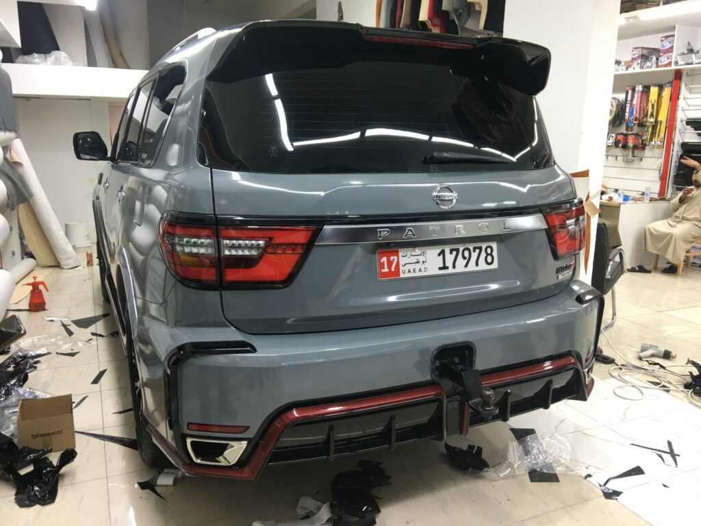 The back of a grey SUV in a workshop, highlighting the application of car wrap and window tint for a sleek finish.