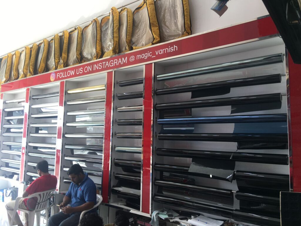 A man seated at a desk with various car parts displayed, representing AlBadiya Car Accessories & Upholstery's services.