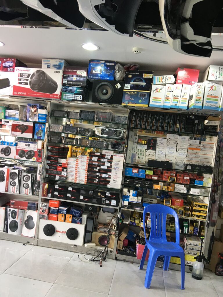 A vibrant shop named AlBadiya Car Accessories & Upholstery showcasing a wide variety of electronics and car accessories.